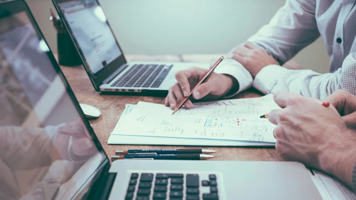 Partner aus allen Branchen Zwei Personen arbeiten mit Laptops und Notizen an einem Schreibtisch