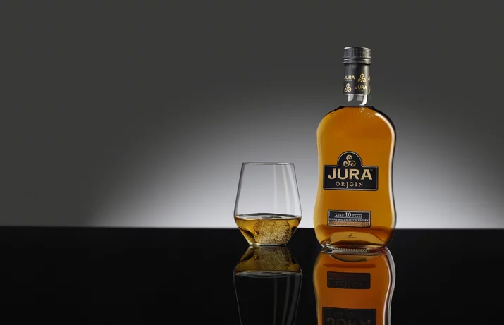 Produktfotografie Jura Whisky Flasche Jura Whisky neben einem gefüllten Glas auf spiegelnder Fläche